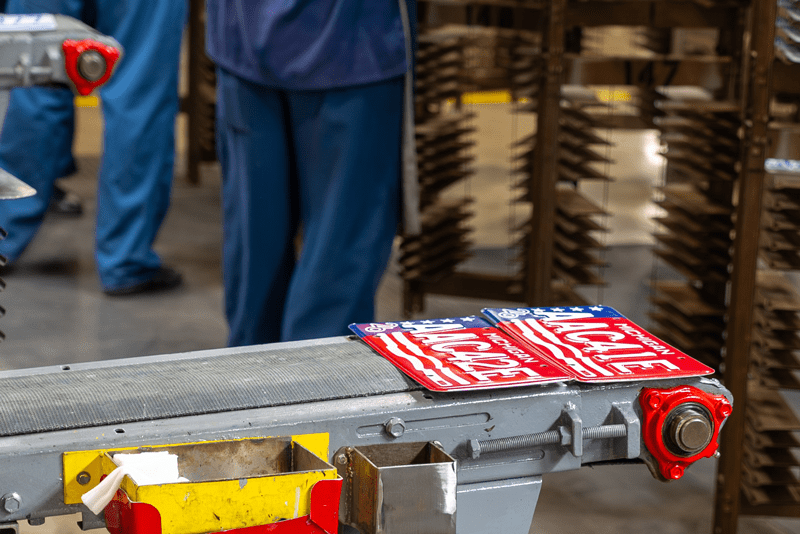 Two brand new license plates sitting on the end of a conveyor belt.