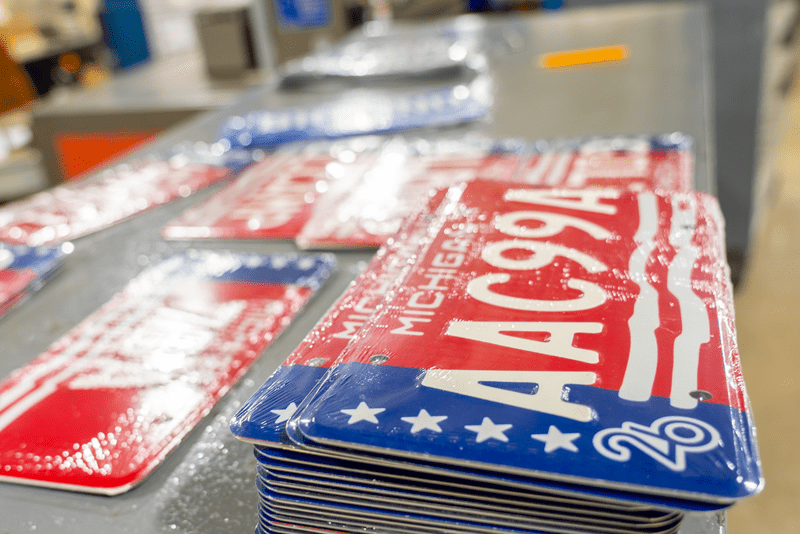 Freshly stamped Michigan license plates covered in plastic shrink wrap.