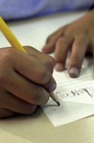 Child writing on paper at school.