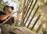 Young man using a rope to climb a structure