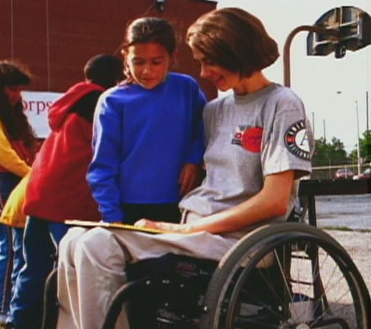 AmeriCorps member in wheelchair reading to a girl