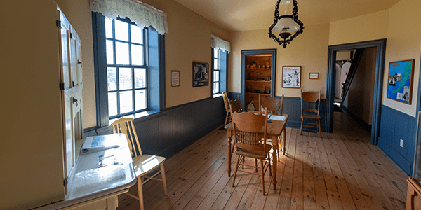 The dining room at Tawas Point Lighthouse with a table and chairs set up to replicate how it may have looked for lighthouse keepers.
