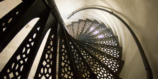 The black metal circular staircase of a lighthouse tower, viewed from looking down from the tower top.