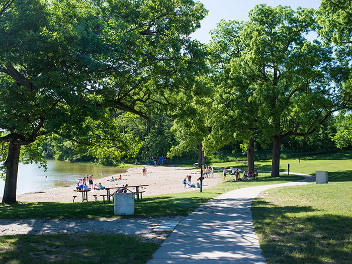 concrete path with visitors playing on sand next to water