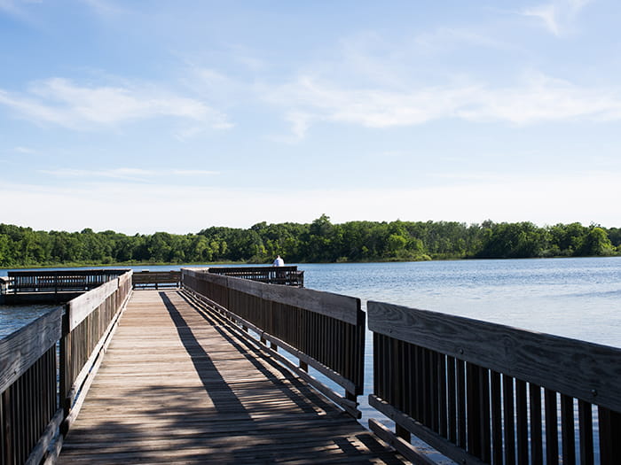 wood fishing pier with visitor fishing at end