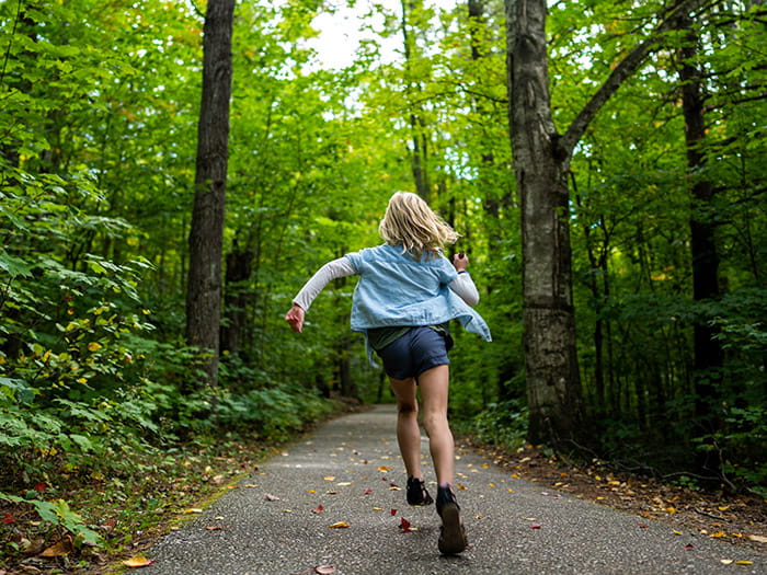 Young girl running down a paved trail