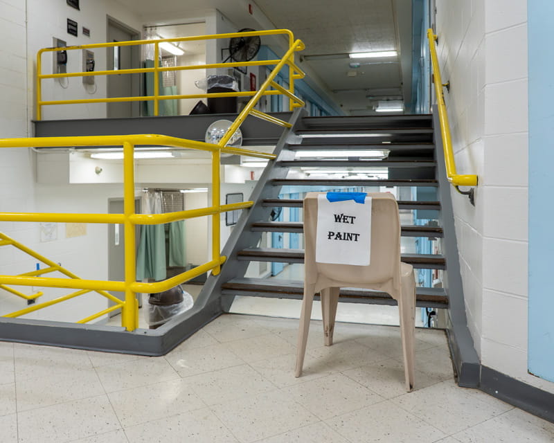 Different floor levels in a prison with a sign that reads "Wet Paint" in the foreground.