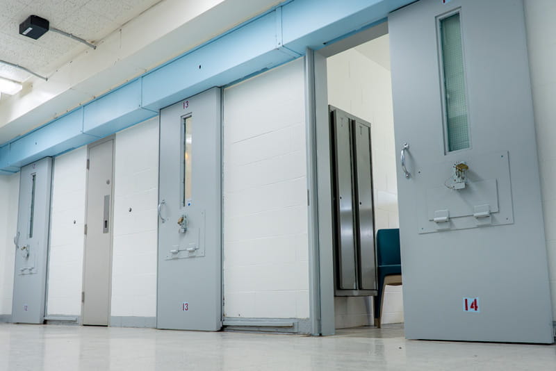 Four prison cell doors with one of them opened.