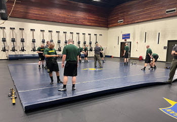 Recruits practice handcuffing in a gym