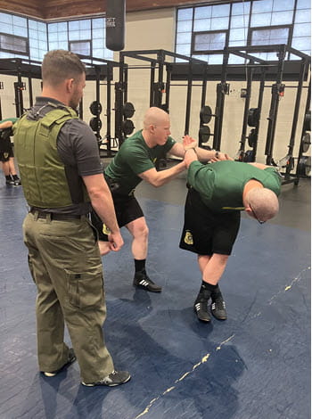 Instructor supervising two men in a gym