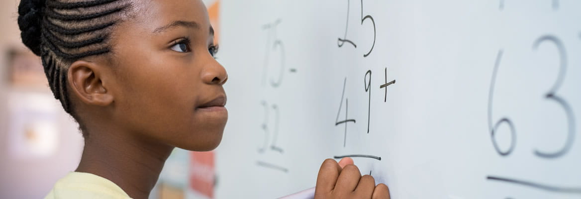 young girl solving a math problem at whiteboard
