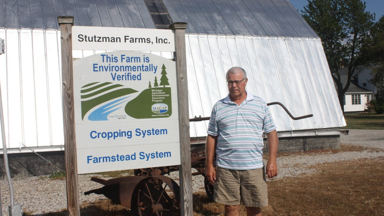 Stutzman standing in front of farm equipment with a sign that says