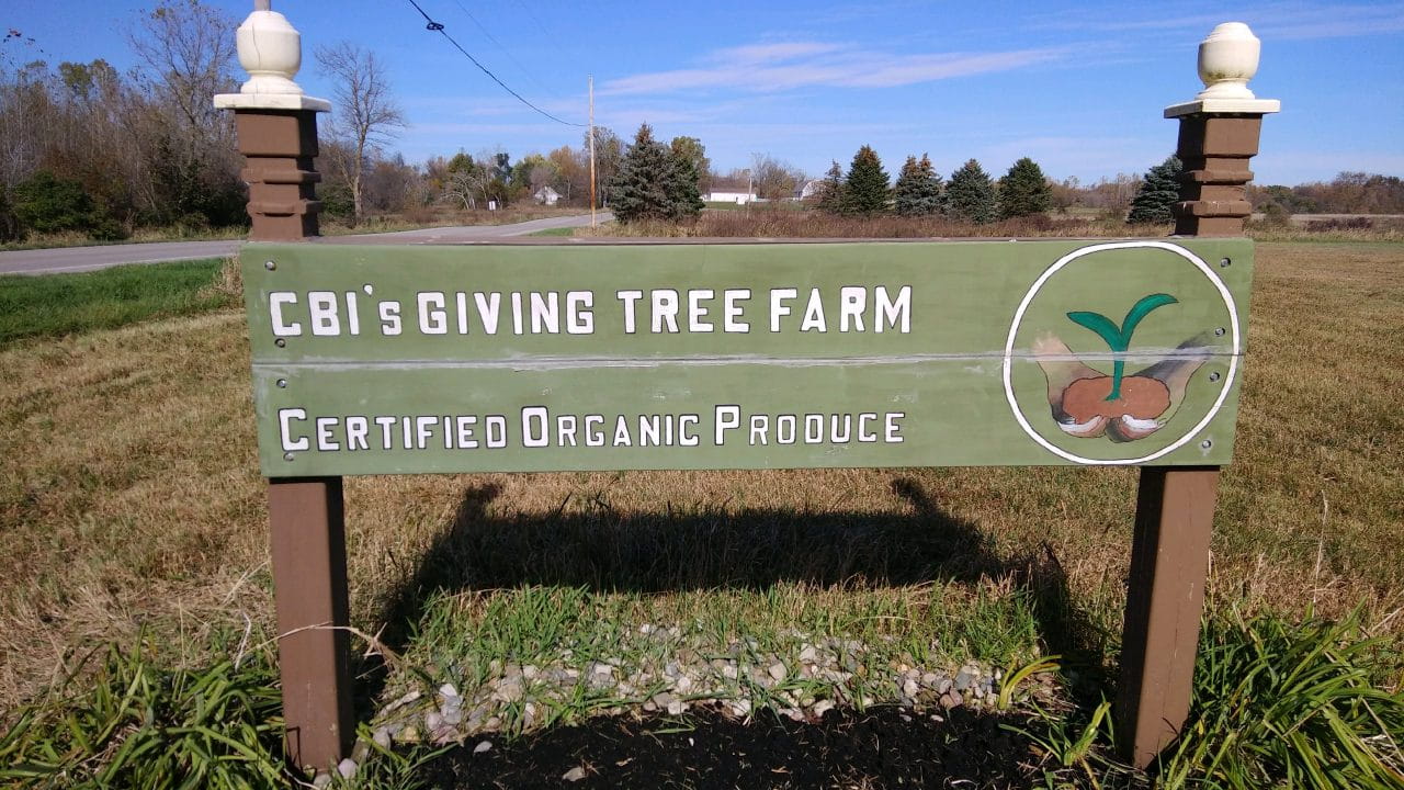 Sign in front of a farm: CBIs Giving Tree Farm. Certified Organic Produce