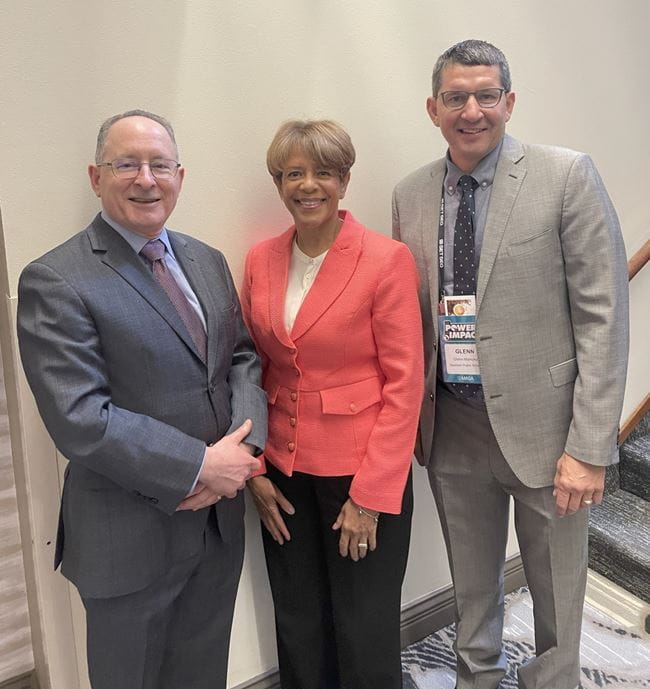 woman and two men standing before wall