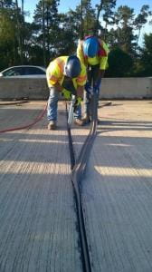 Road construction showing two workers creating a joint seal. 