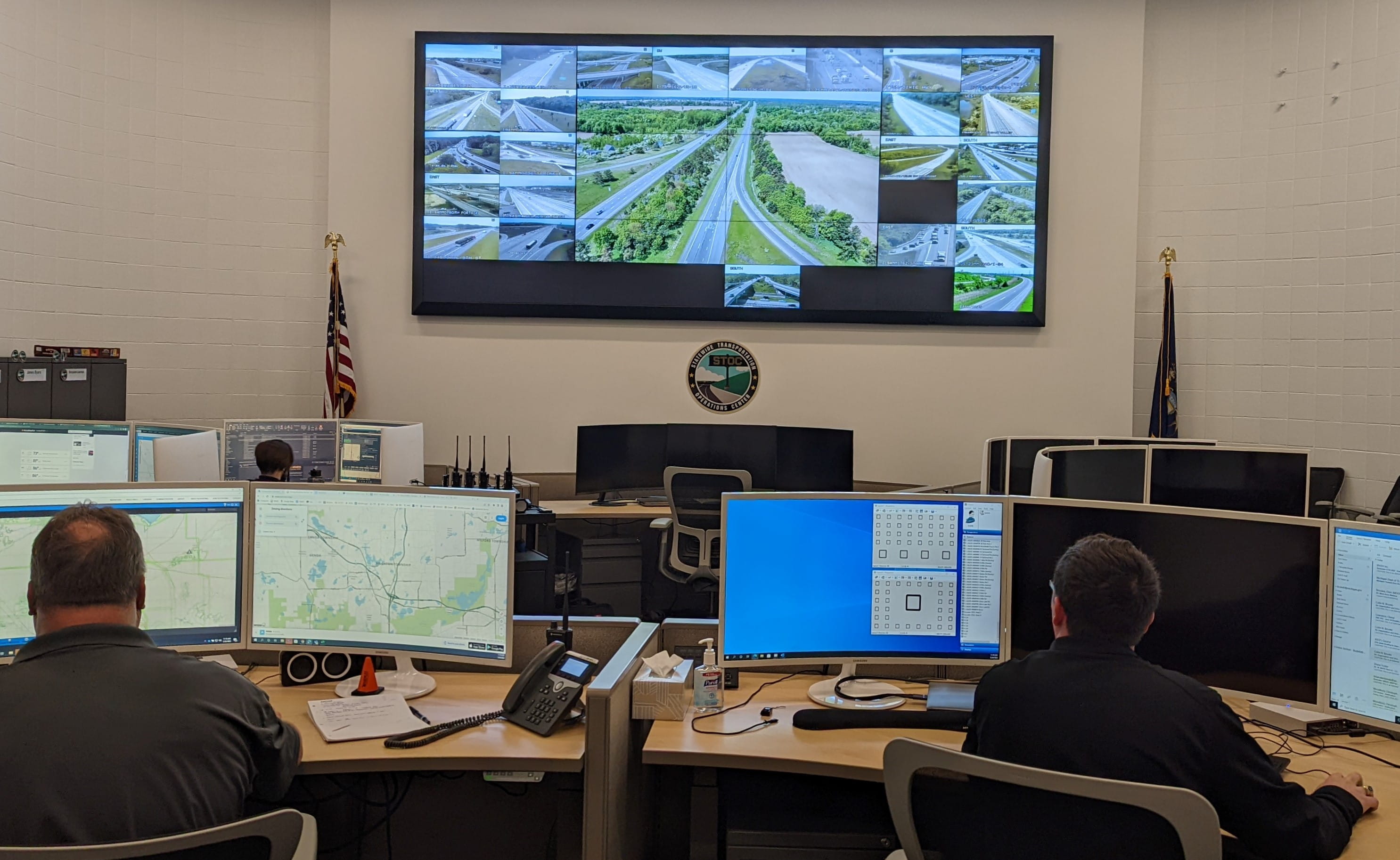 A traffic operations center with staff viewing multiple traffic images on a large screen.