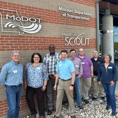 ENTERPRISE pooled fund members standing in front of a building with the signage “Missouri Department of Transportation,” “Kansas City SCOUT” and MoDOT logo.