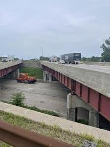 Bridge over a multilane interstate highway shows damaged fascia.