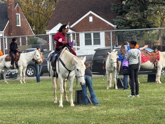 Elementary student smiling as they get off of a white horse at a Lights On Afterschool event