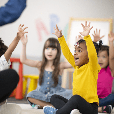 Photograph of cheering children with their hands raised