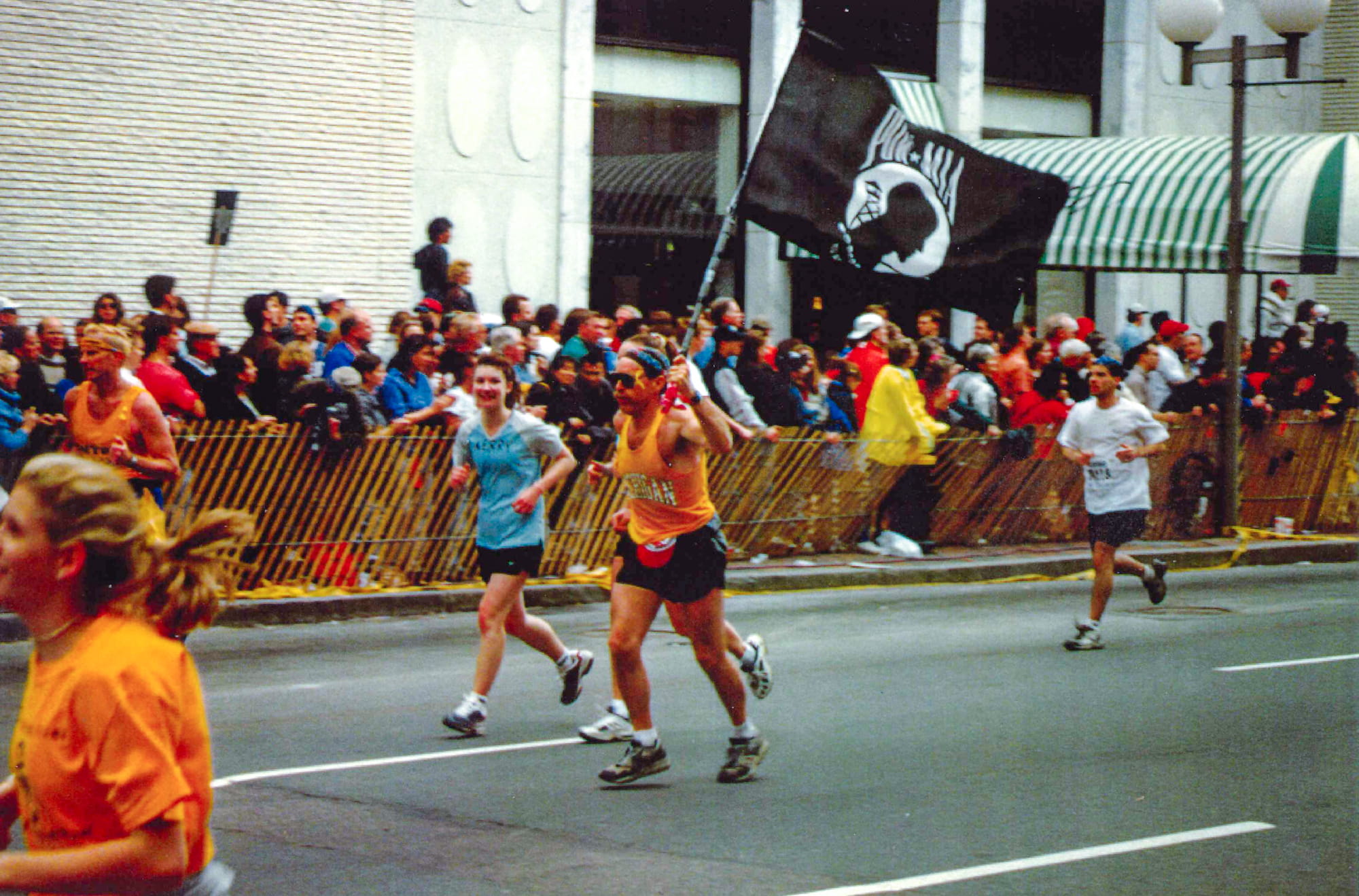 light-skinned man carrying pow flag running street race