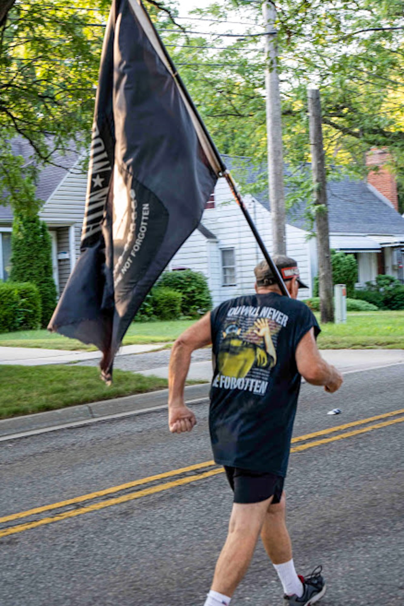 light-skinned man holding pow flag and running street race