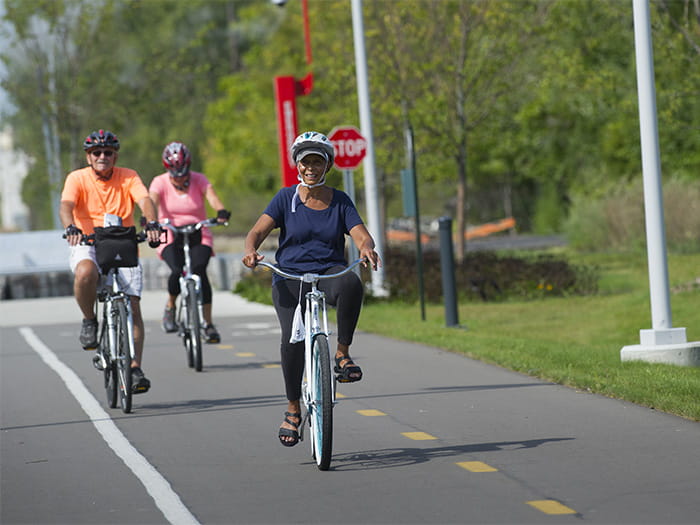 three bikers riding on paved trail